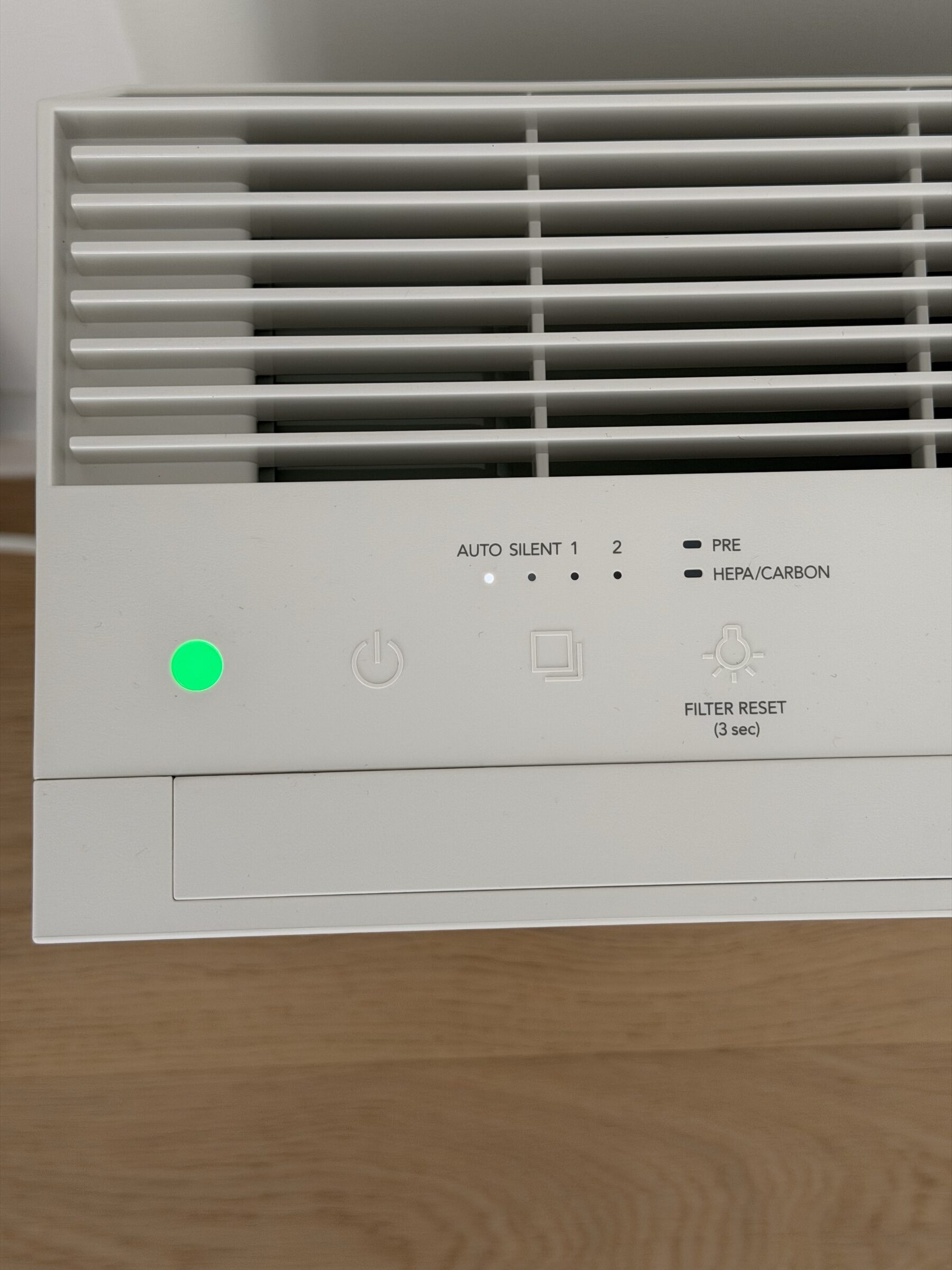 Top-down close-up of the Coway Airmega 150 control panel showing AUTO, SILENT, 1, and 2 mode indicators with a green air-quality status LED illuminated