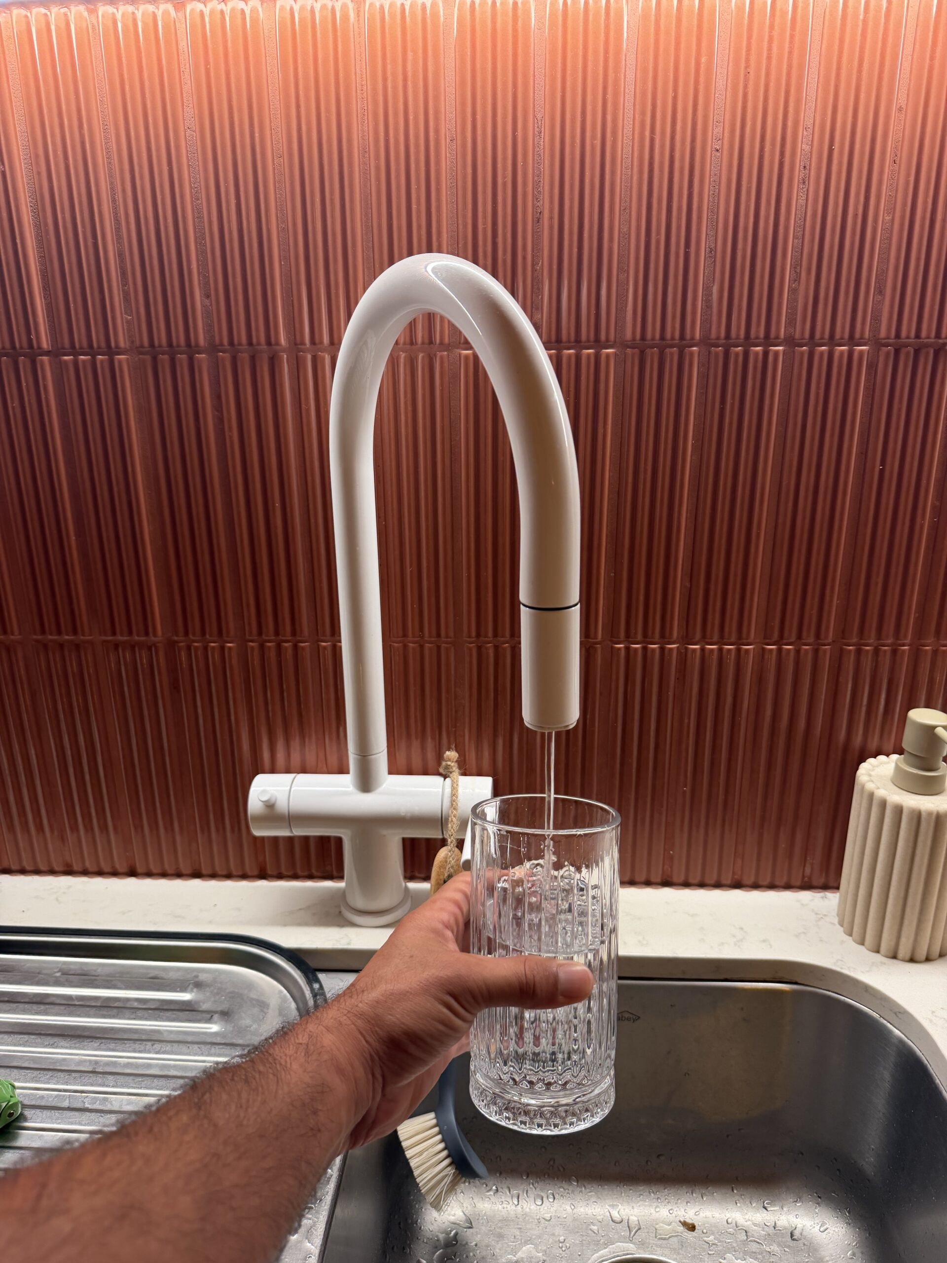 Filling a glass of water from the dedicated EcoHero 5 RO faucet at Palm Beach QLD