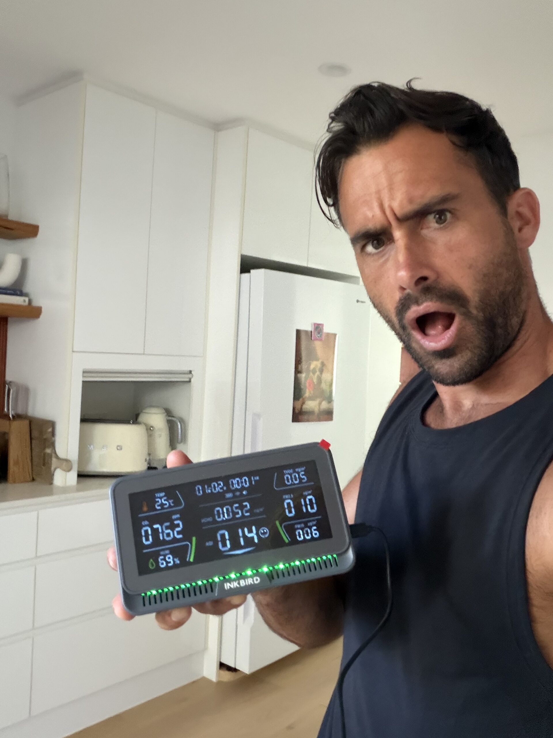 Jayce Love holding Inkbird air quality monitor -- CO2 762ppm, AQI 14, PM2.5 10ug/m3, Palm Beach QLD kitchen ambient baseline