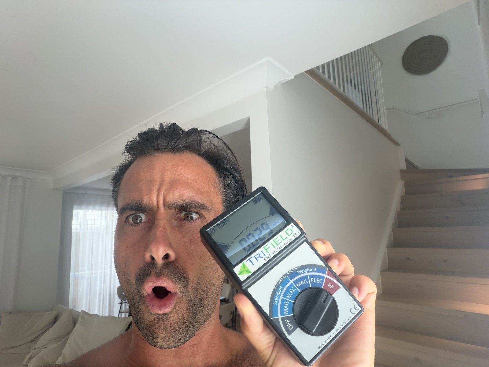 Jayce Love holding a TriField TF2 EMF meter showing a live RF reading during a home EMF audit